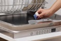 female hand puts dishwasher tablet into open dishwasher machine Royalty Free Stock Photo