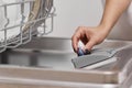 female hand puts dishwasher tablet into open dishwasher machine Royalty Free Stock Photo