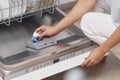 female hand puts dishwasher tablet into open dishwasher machine Royalty Free Stock Photo