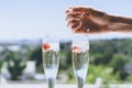 Female hand puts ice into a glasses champagne with strawberry inside on sunny terrace overlooking beautiful view at Royalty Free Stock Photo