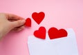 Female hand puts paper red hearts in a white envelope. Love letter. Valentine`s day concept. Happy Valentine's day