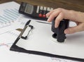 A female hand puts a seal on a blank sheet contract