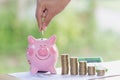 Female hand putting a coin into piggy bank , for invest money, I Royalty Free Stock Photo