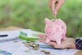 Female hand putting a coin into piggy bank , for invest money, I Royalty Free Stock Photo