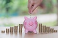 Female hand putting a coin into piggy bank , for invest money, I Royalty Free Stock Photo