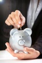 Female hand putting coin in piggy bank