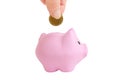 Female hand putting a coin into piggy bank on white isolated background. Pink piggy bank. Royalty Free Stock Photo