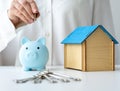 Female hand putting coins in piggy bank. Savings for buy own home concept Royalty Free Stock Photo