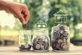 female hand putting money coins in glass jar concept saving for Royalty Free Stock Photo