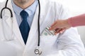 Female hand putting money in doctor pocke, closeup Royalty Free Stock Photo