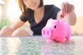 Female hand putting money into piggy bank. Royalty Free Stock Photo