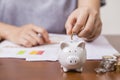 Female hand putting money into piggy bank for saving money Royalty Free Stock Photo