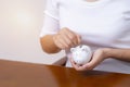 Female hand putting money into piggy bank for saving money Royalty Free Stock Photo