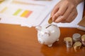 Female hand putting money into piggy bank for saving money wealth and financial, business, investment, retirement, saving for the Royalty Free Stock Photo