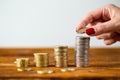 Female hand putting two euros onto stack on wooden table. Royalty Free Stock Photo