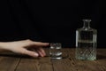 Female hand reaches for a glass with alcohol, black background alcohol Royalty Free Stock Photo