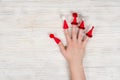 Female hand with red Christmas caps on fingers with hats with buboes on a wooden white background. Crezi new year. Place