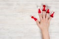 Female hand with red Christmas caps on fingers with hats with buboes on a wooden white background. Crezi new year. Place