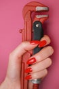 Female hand with a red nails holding a plumbing wrench. Royalty Free Stock Photo