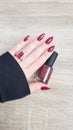 Female hand with red long nails and a bottle Royalty Free Stock Photo