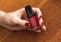 Female hand with red manicure holding bottle of nail Polish Royalty Free Stock Photo