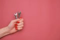 Female hand with a red manicure and a wrench on on a red background. Royalty Free Stock Photo