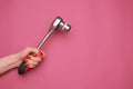 Female hand with a red manicure and a wrench wheel on a pink background. Royalty Free Stock Photo