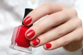 Female hand with red nail design holding nail polish bottle Royalty Free Stock Photo