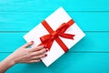Female hand with red nails on gift box on blue wooden background. Top view and copy space Royalty Free Stock Photo