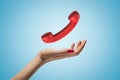 Female hand with red retro telephone receiver on blue background Royalty Free Stock Photo