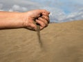 Female hand with sand against the Dunes of Maspalomas with blue sky and clouds in the background Royalty Free Stock Photo