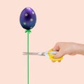 Female hand with scissors and egg like balloon