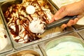 Female hand with scoop takes ice cream from the fridge and serving in ceramic white cups.