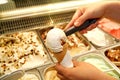Female hand with scoop takes ice cream from the fridge and serving in waffle cone. Woman taking scoop of tasty ice cream.