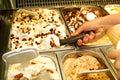 Female hand with scoop takes ice cream from the fridge and serving in waffle cone. Woman taking scoop of tasty ice cream.