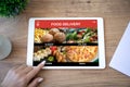 Female hand selects menu on computer tablet food delivery application Royalty Free Stock Photo