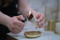 Female hand sets fire to incense on a copper bowl. Aroma therapy, to relax after a hard day. Smells for concentration