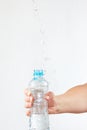 Female hand shaking bottle of mineral water with a splash Royalty Free Stock Photo