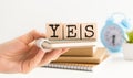 Female hand showing the word Yes on a wooden cube without text, did not choose to stand on the table Royalty Free Stock Photo