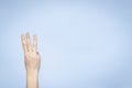 Female hand shows number three. Woman hand showing three fingers, pointing fingers up on light blue background Royalty Free Stock Photo