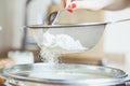 Female hand sift flour through sieve