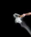 Female hand sifts white wheat flour through a round wooden sieve on a black background Royalty Free Stock Photo