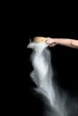 Female hand sifts white wheat flour through a round wooden sieve on a black background Royalty Free Stock Photo