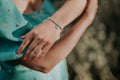 Female hand with silver beads bracelet and blue heart charm. Turquoise jewelry accessories. Retro styled dress.