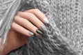 Female hand with silver nail design. Glitter black nail polish manicure. Woman hand hold gray wool shawl
