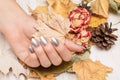 Female hand with silver nail design. Silver nail polish manicured hand. Woman hand hold yellow autumn leaf
