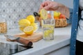 Female hand with slice of lemon in kitchen, with sparkling water with lemon Royalty Free Stock Photo