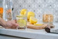 Female hand with slice of lemon in kitchen, with sparkling water with lemon Royalty Free Stock Photo