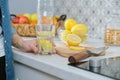 Female hand with slice of lemon in kitchen, with sparkling water with lemon Royalty Free Stock Photo