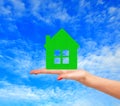 Female hand with small model of house over blue sky Royalty Free Stock Photo